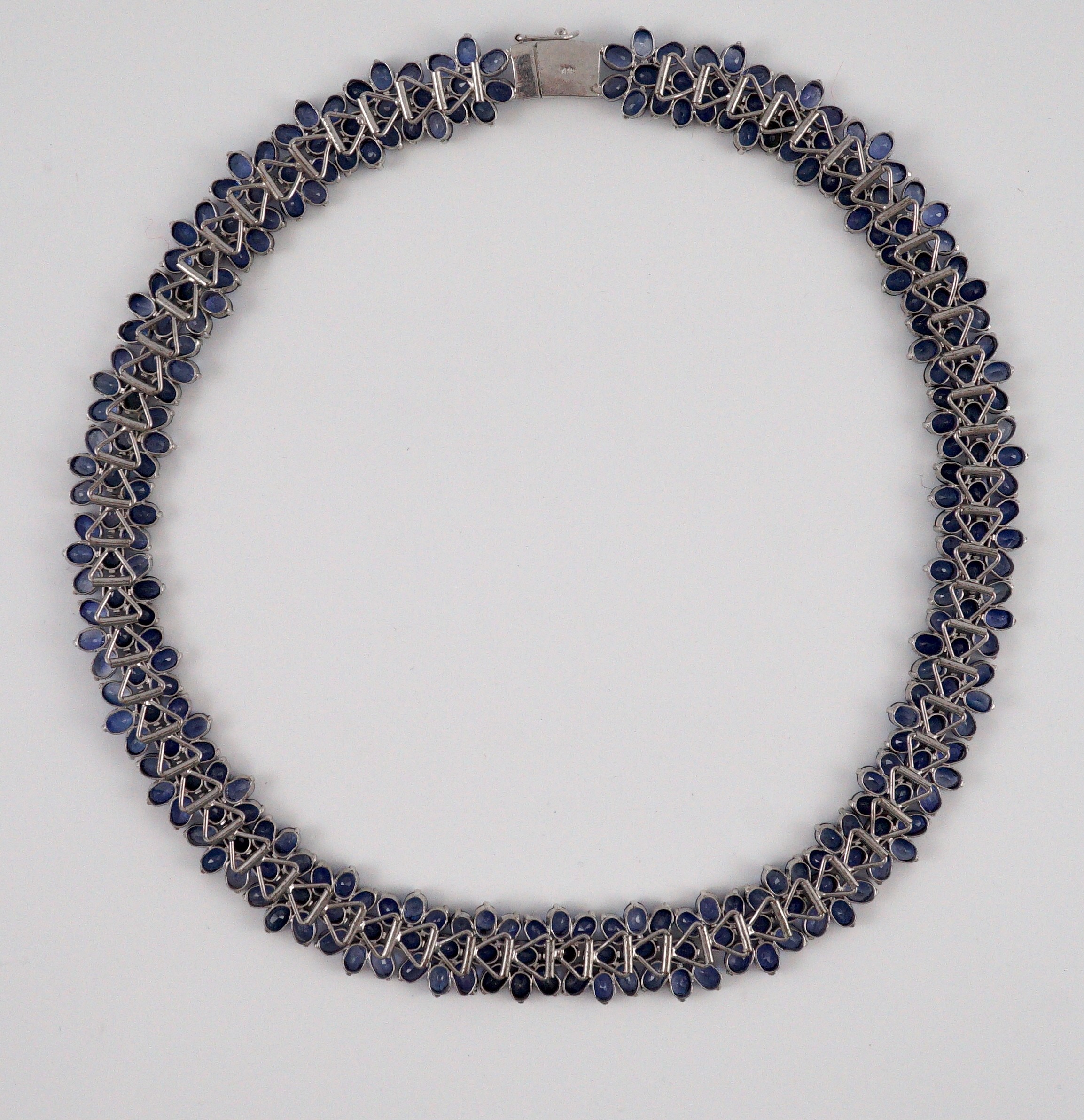 An 18K white gold and synthetic sapphire? flower head cluster set necklace